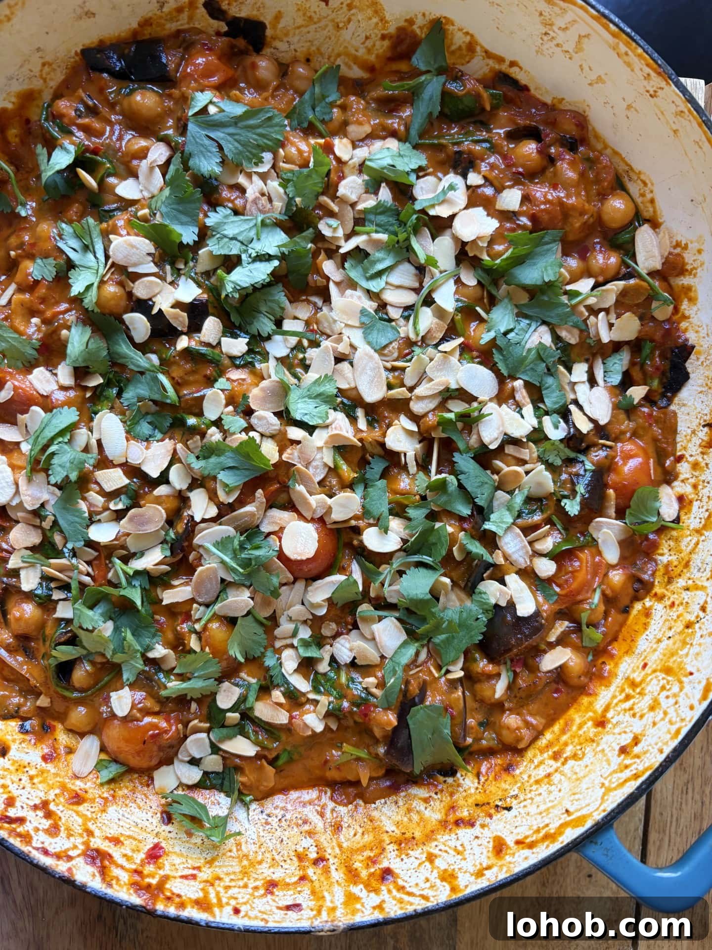 aubergine curry in pan with coriander and flaked almonds.