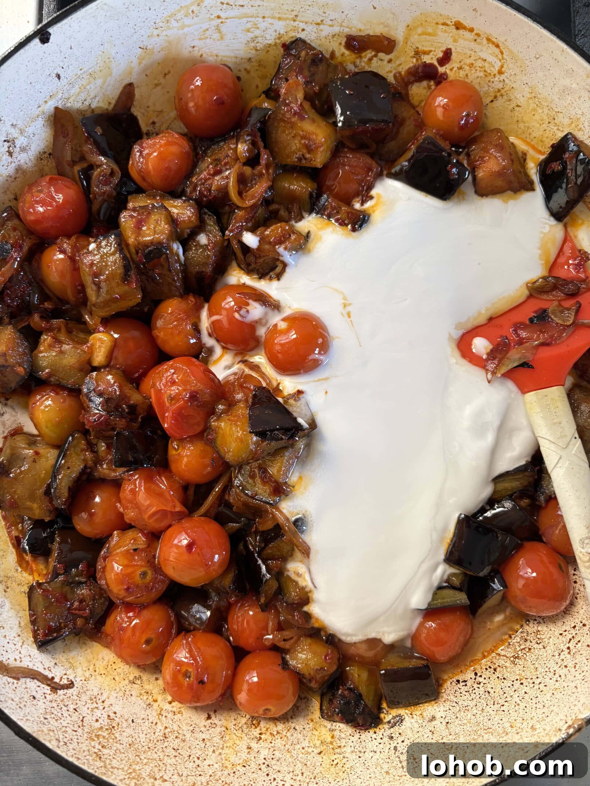 adding coconut milk to the aubergine curry.