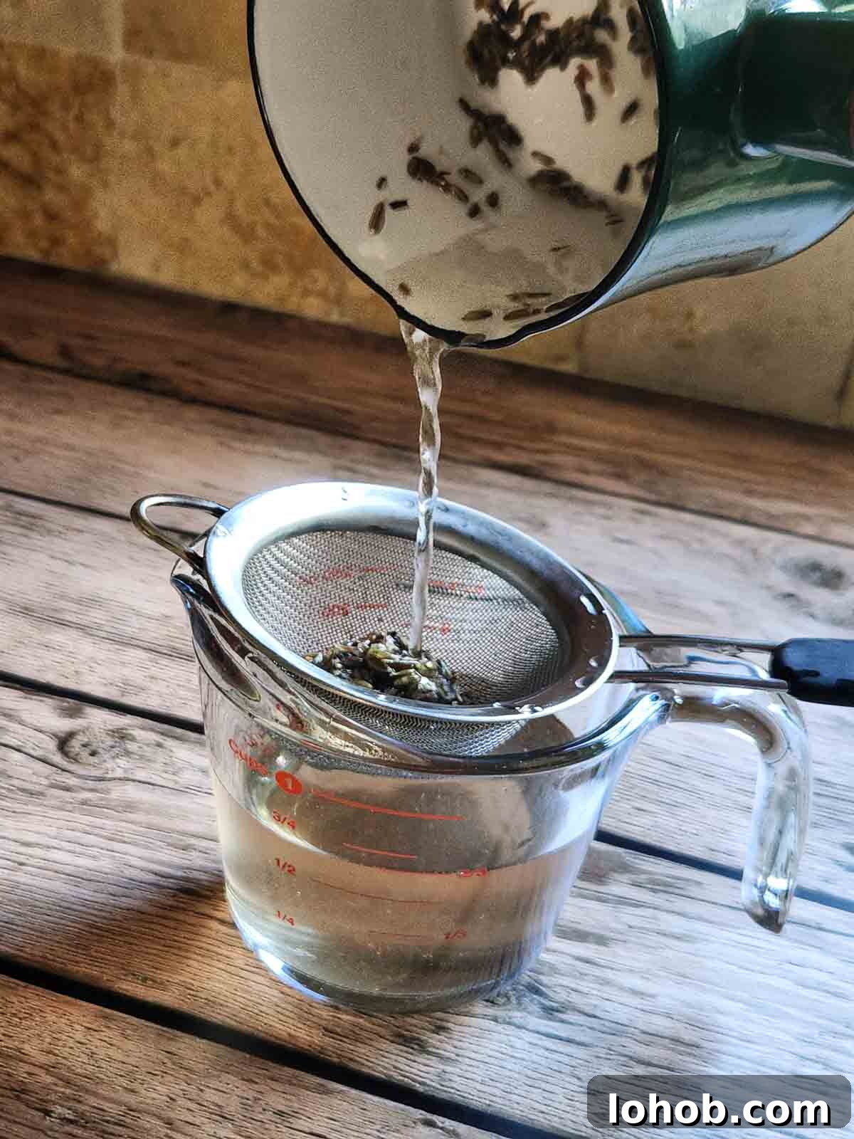 Straining lavender simple syrup into a clear glass.