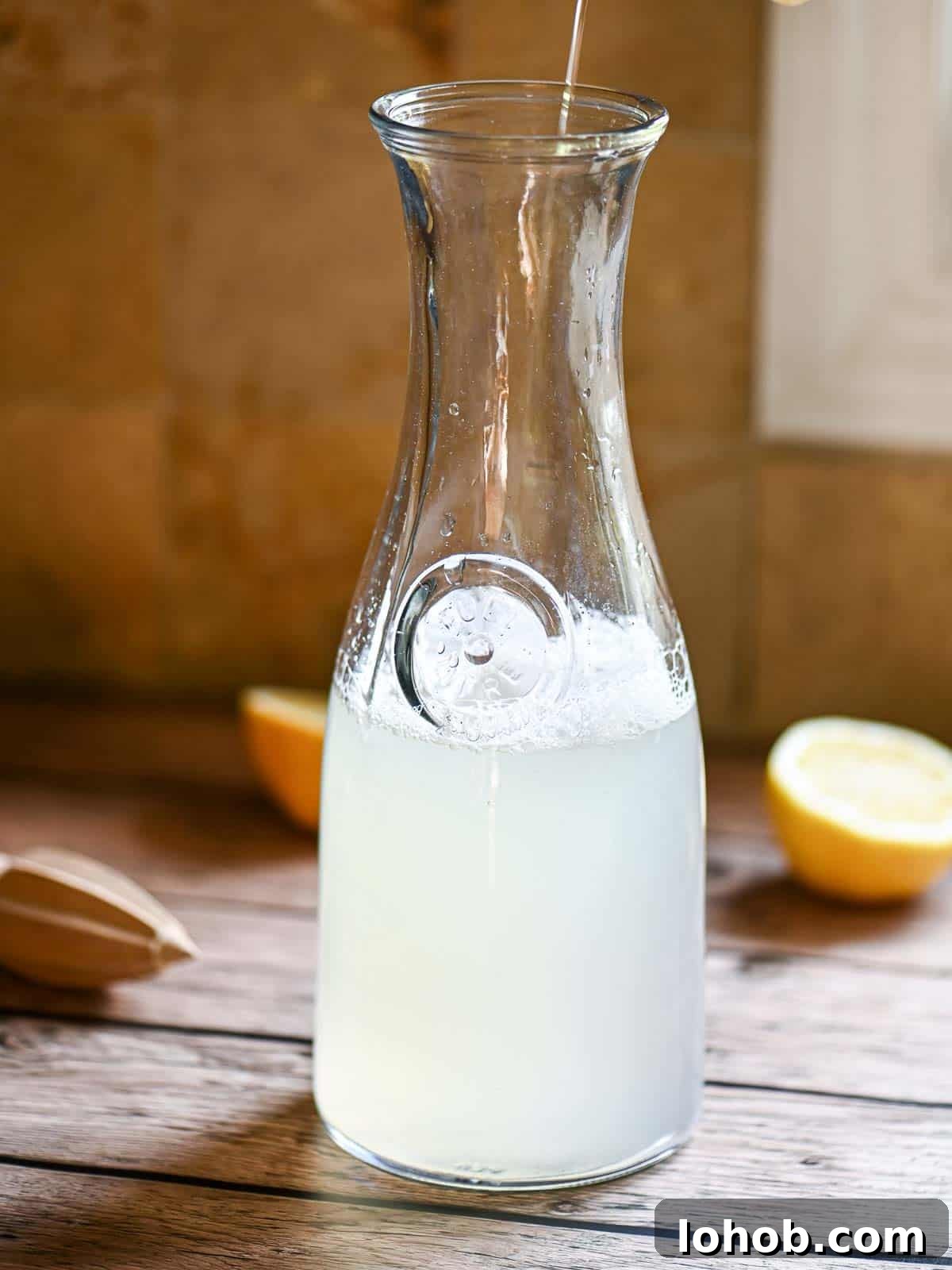 A pitcher filled with lemonade on a wooden table.