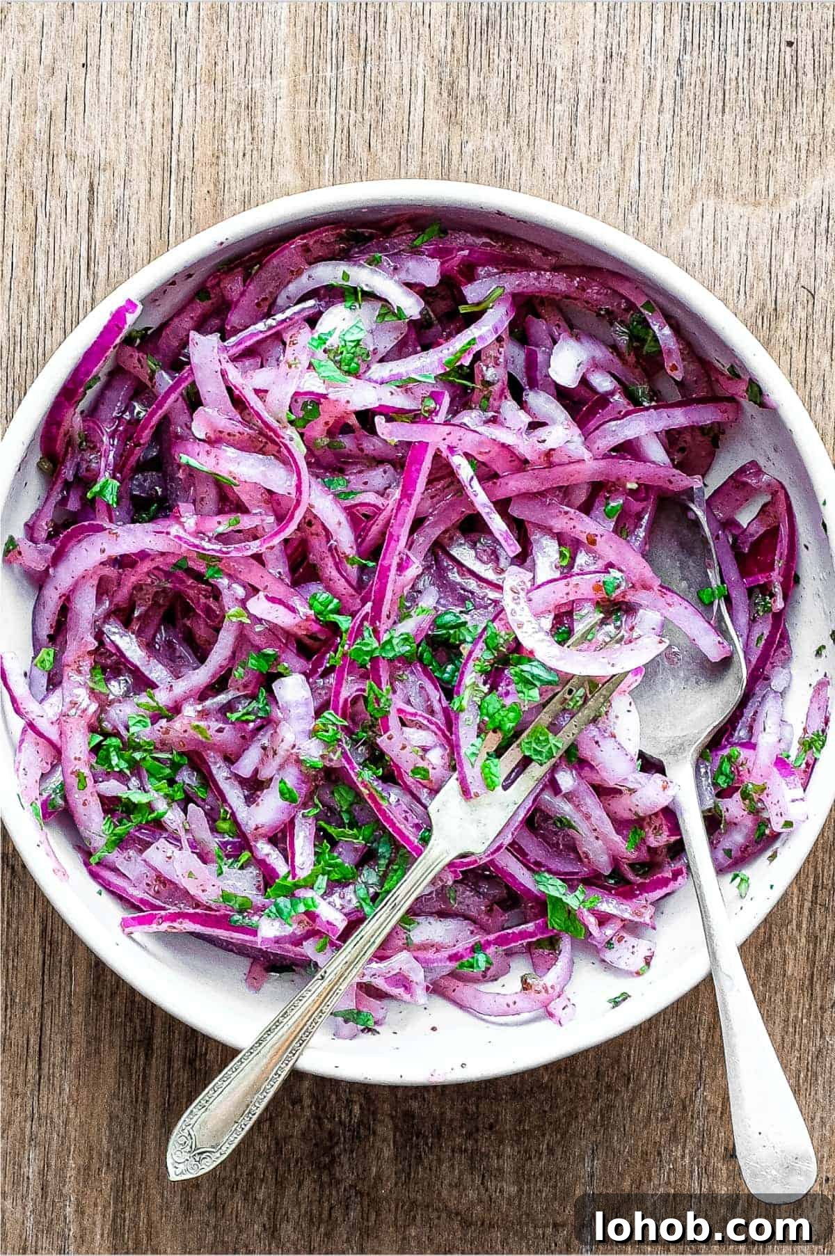 A small bowl of Sumac Onions with a small serving fork and spoon