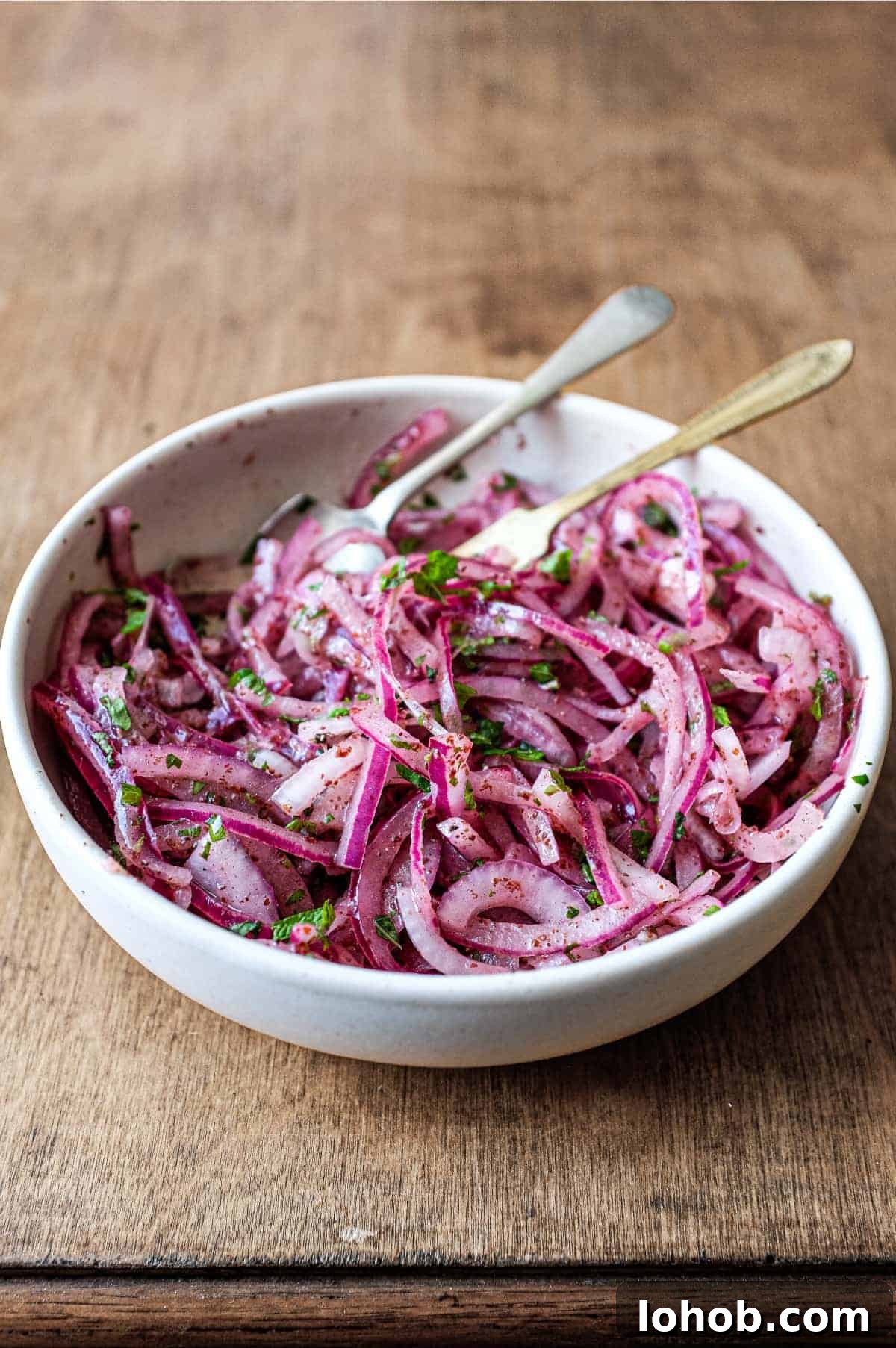 A small bowl of Sumac Onions with a small serving fork and spoon