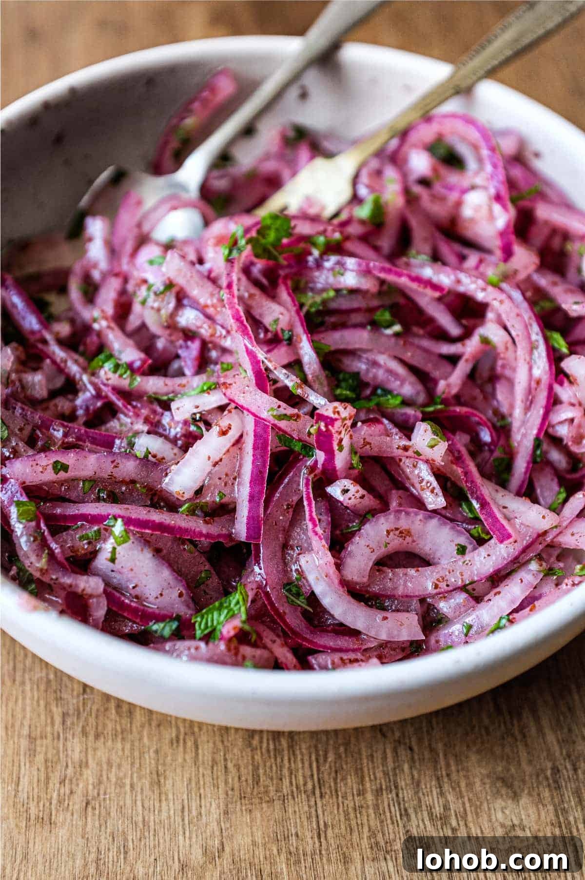 A small bowl of Sumac Onions with a small serving fork and spoon