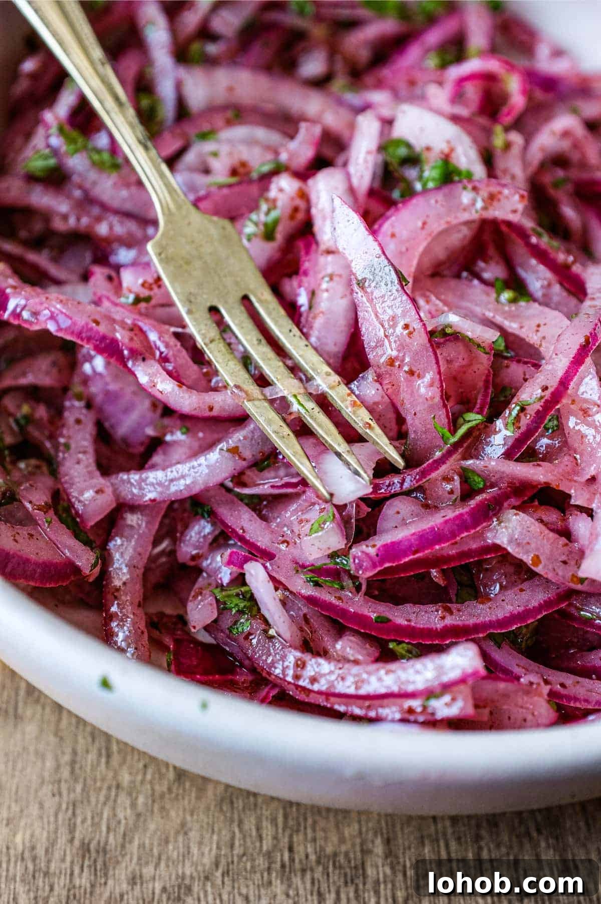 A small bowl of Sumac Onions with a small serving fork and spoon