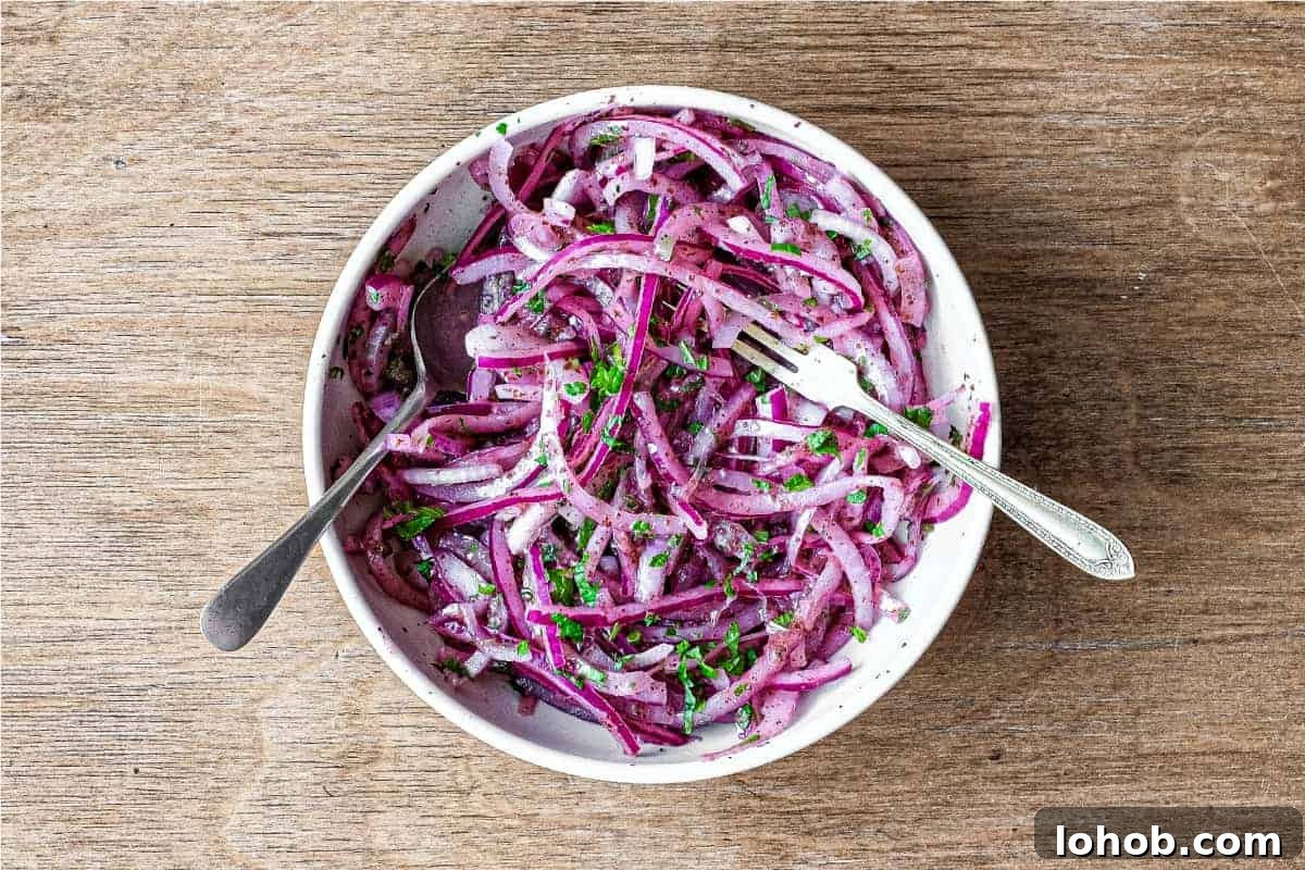 A small bowl of Sumac Onions with a small serving fork and spoon