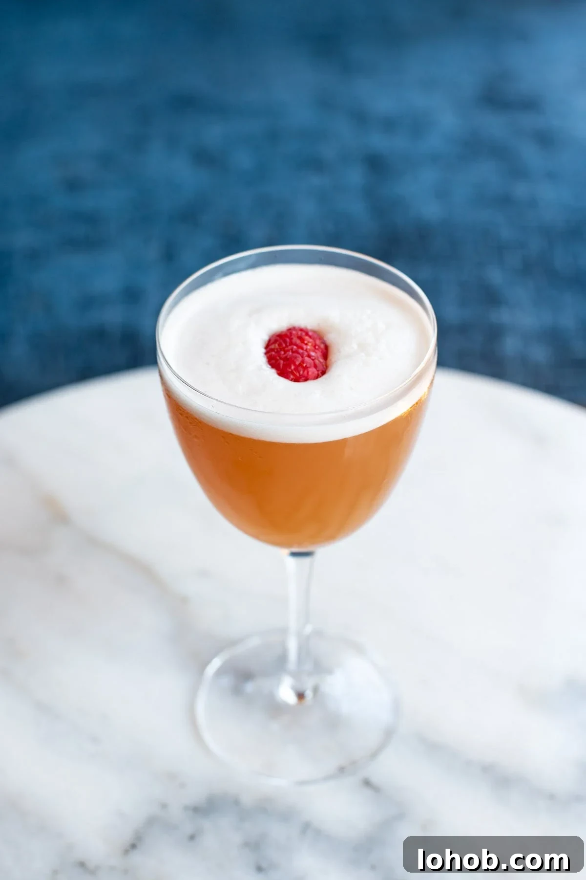 A French Martini garnished with a raspberry pictured on a marble table.