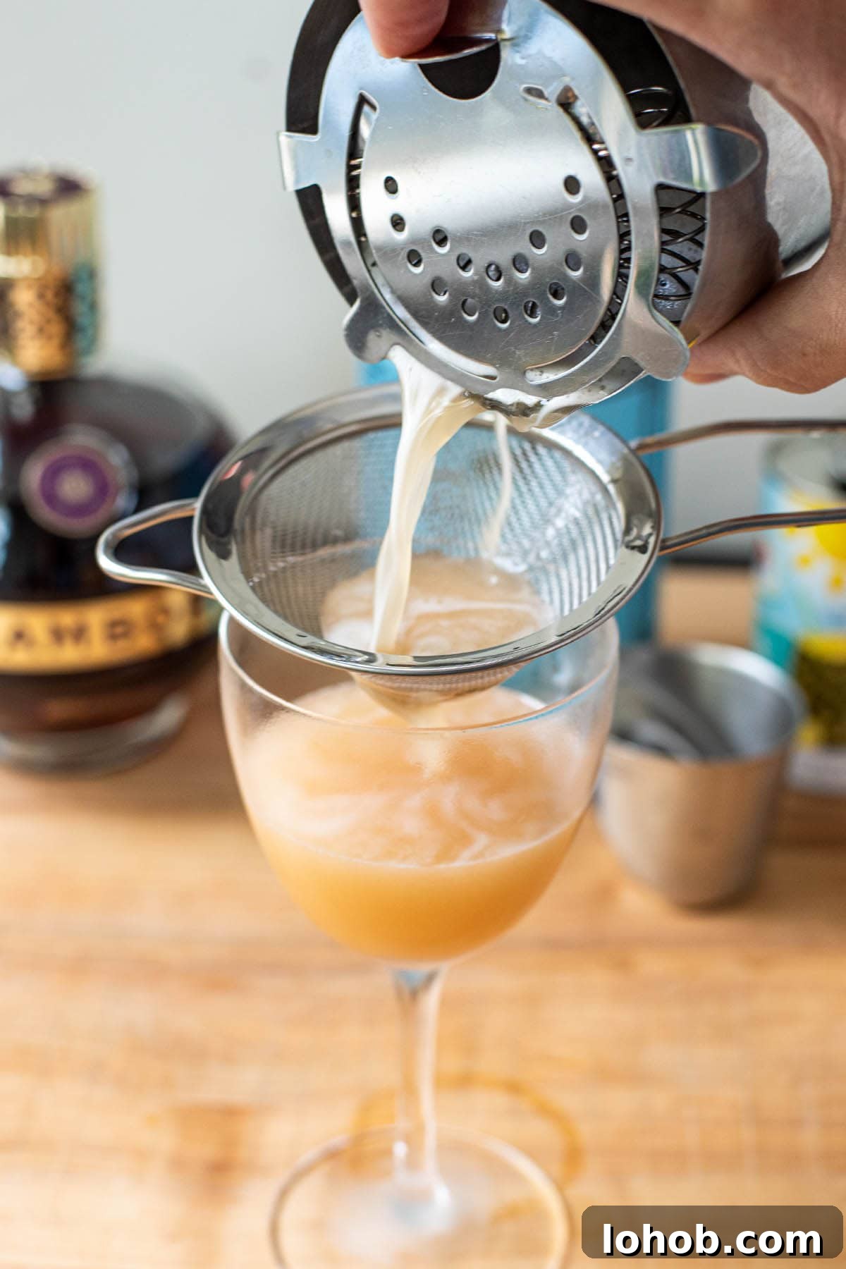 Double straining a French Martini into a chilled Nick and Nora glass.