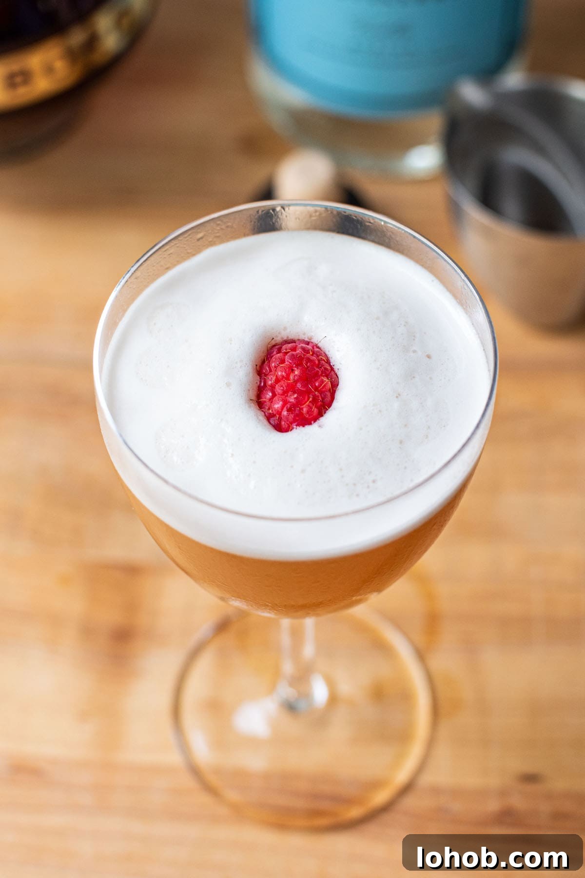 Garnishing a frothy French Martini with a halved raspberry.