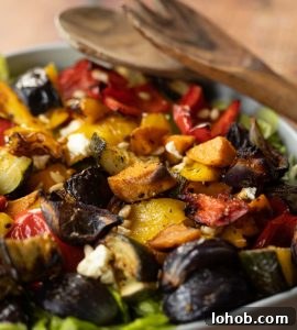 close up shot of salad in bowl with salad tosser resting on dish in background