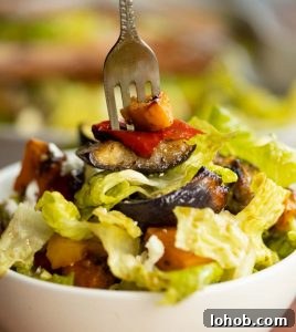 closeup shot of silver fork digging into small bowl of salad