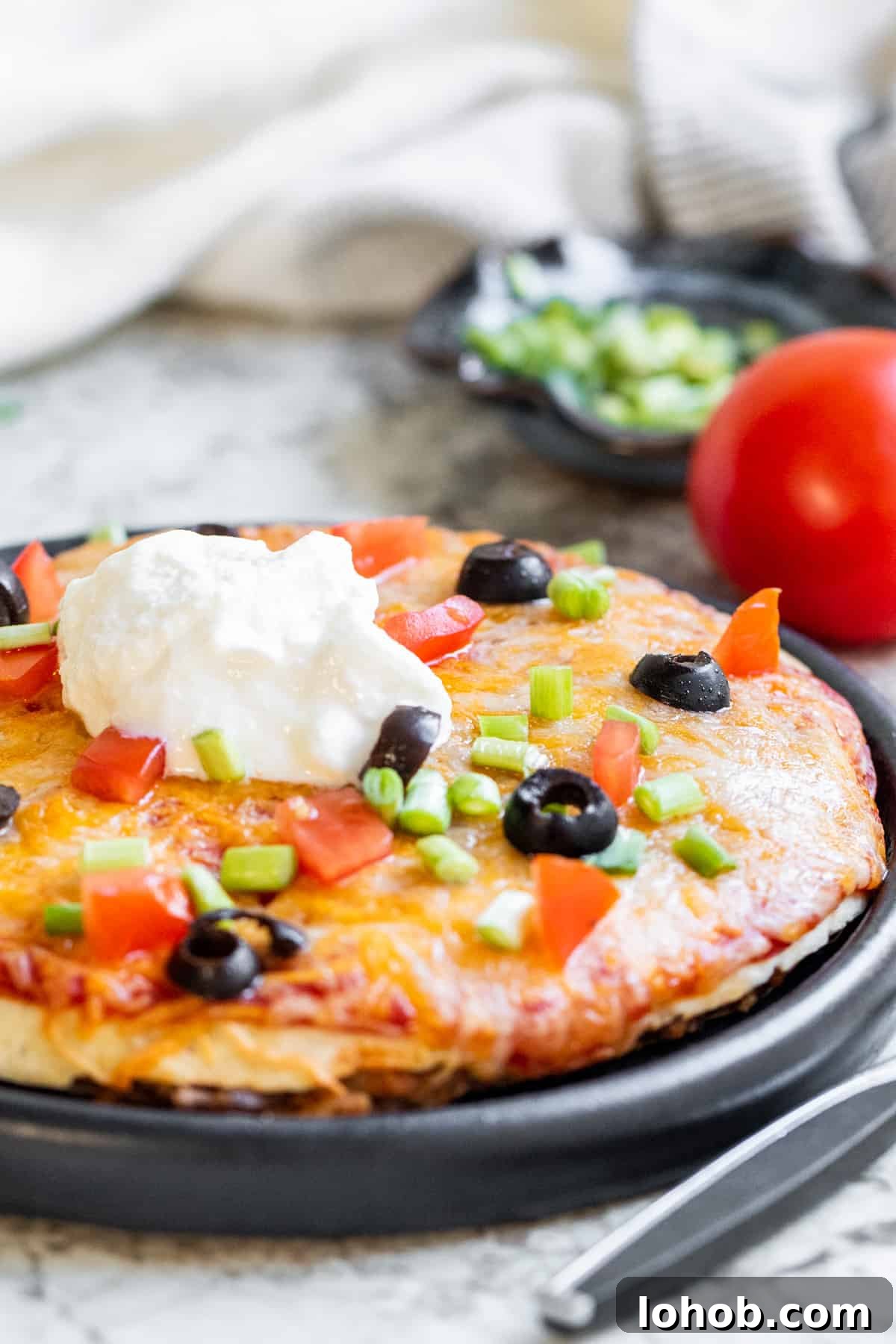 Crispy Air Fryer Mexican Pizza Recipe (30 Minutes) 2 Mexican pizza on a black plate on a white counter.