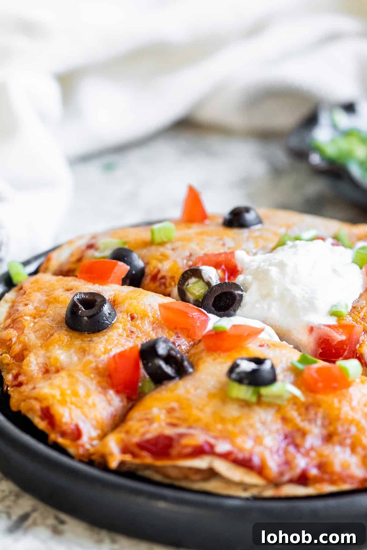 Crispy Air Fryer Mexican Pizza Recipe (30 Minutes) 6 Close up shot of taco pizza sliced on a black plate.