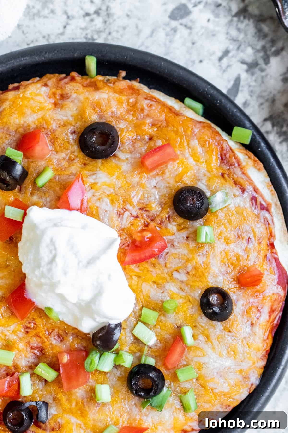 Crispy Air Fryer Mexican Pizza Recipe (30 Minutes) 7 Overhead shot of taco bell Mexican pizza on a black plate.