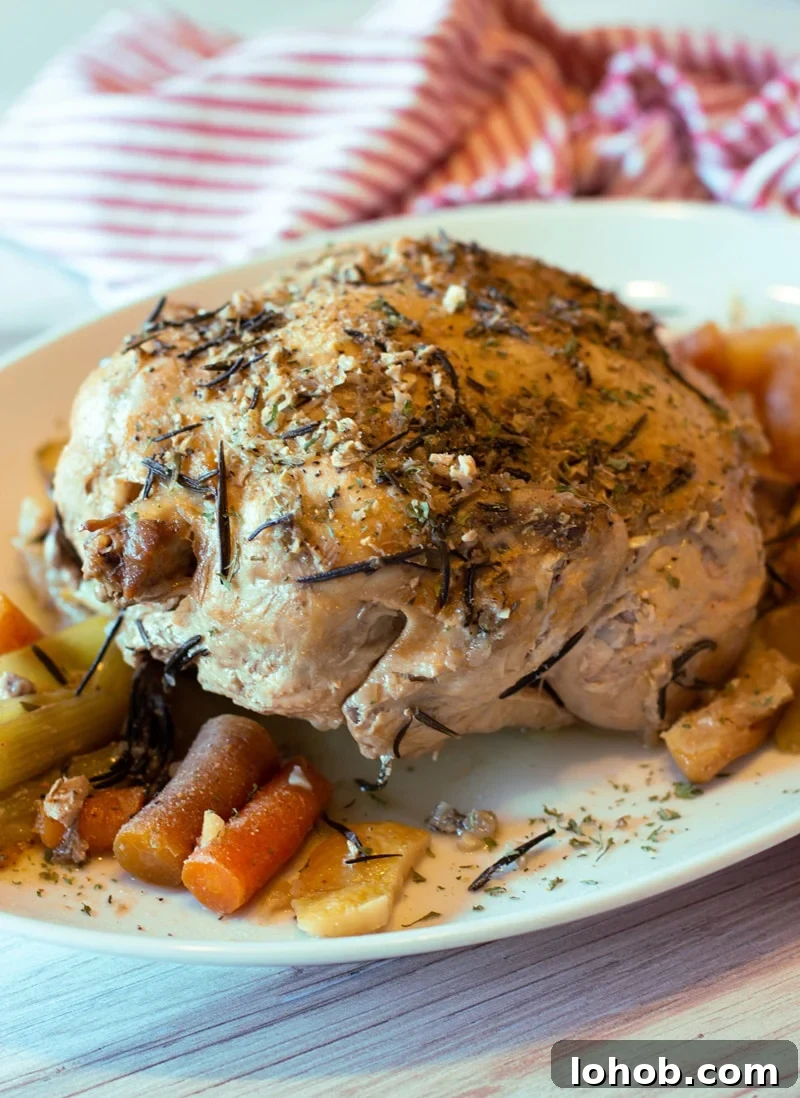 Slow Cooker Lemon Garlic Whole Chicken Recipe 2 Whole chicken sitting on a platter topped with fresh rosemary.
