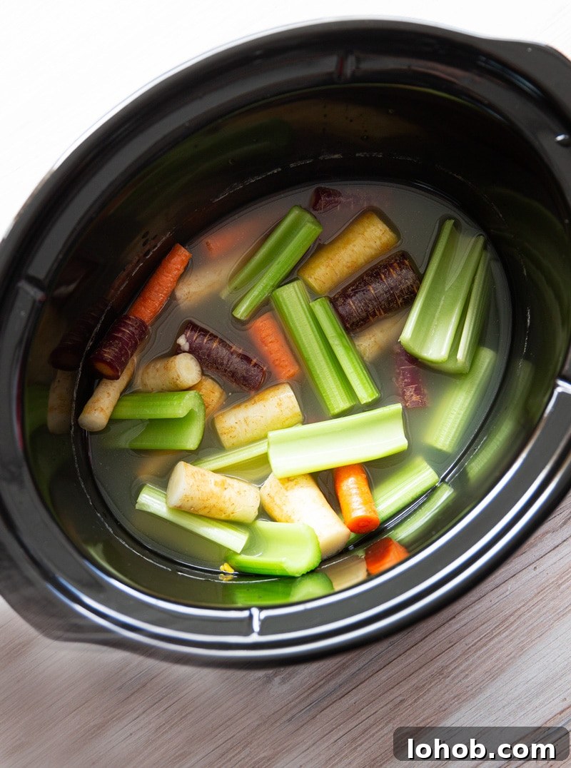 Slow Cooker Lemon Garlic Whole Chicken Recipe 5 Crock pot filled with carrots, celery, and chicken broth.