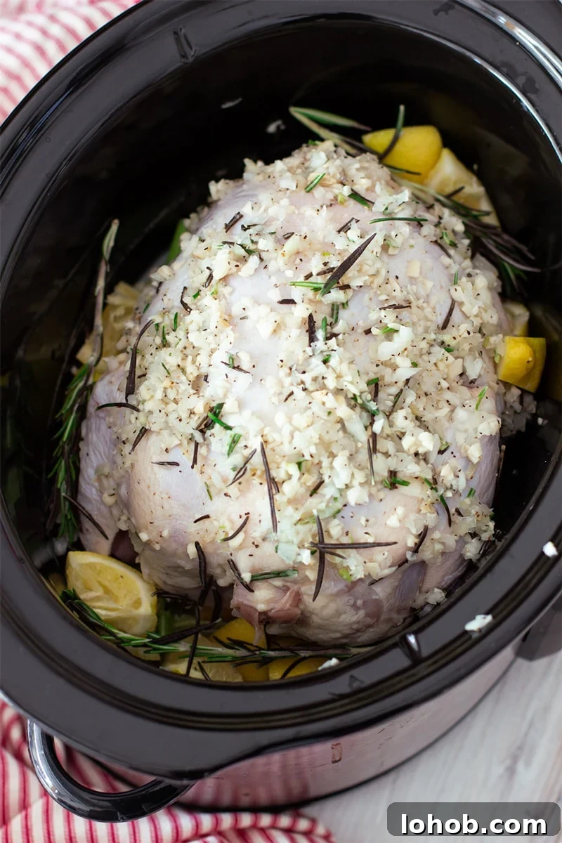 Slow Cooker Lemon Garlic Whole Chicken Recipe 7 Whole Chicken in a slow cooker topped with herbs and lemon.