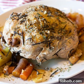 Slow Cooker Lemon Garlic Whole Chicken Recipe 9 Whole chicken sitting on a platter topped with fresh rosemary.
