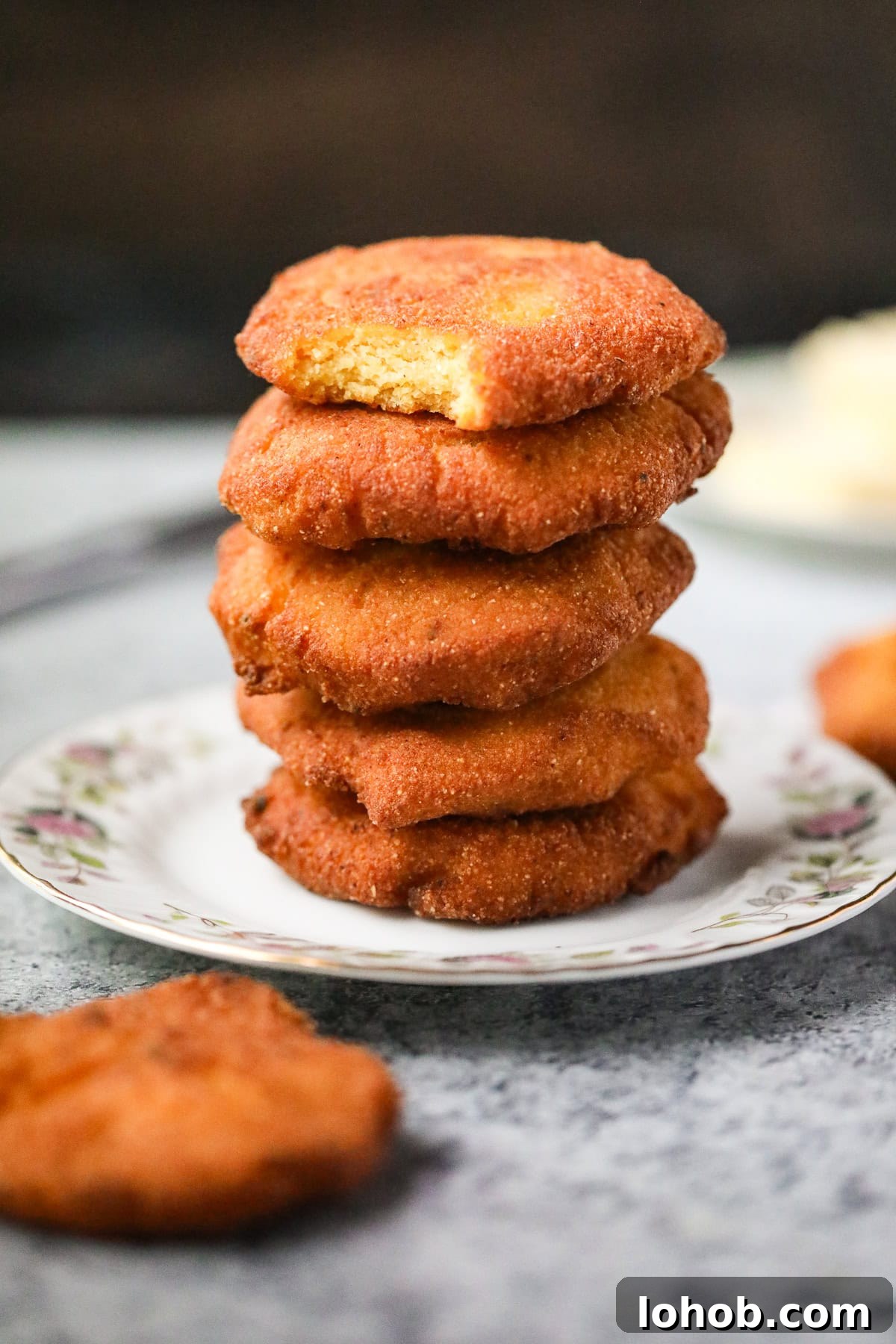 Southern Hot Water Cornbread Recipe — Crispy Skillet Cornbread 2 Hey stack of hot water cornbread patties on a plate.