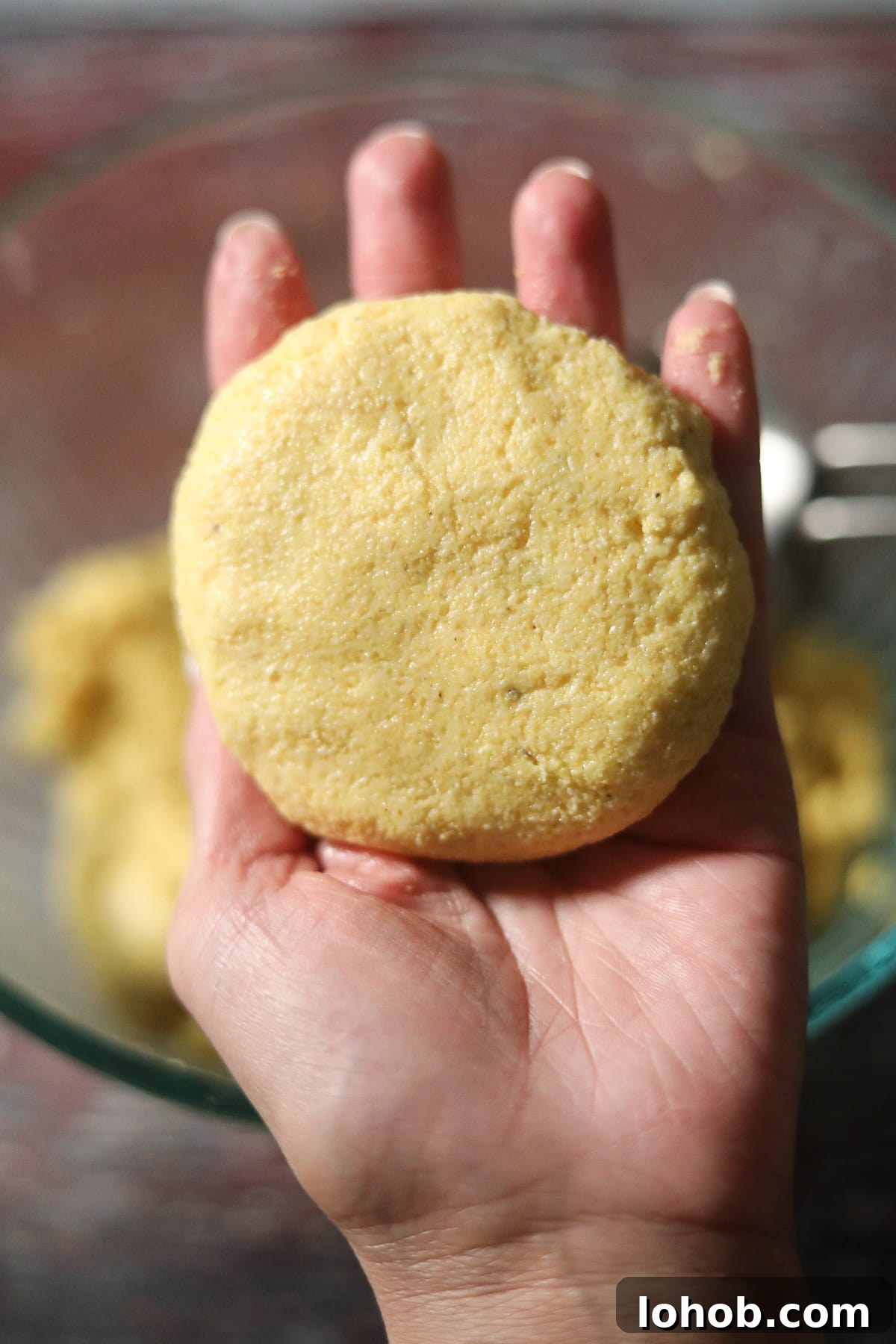 Southern Hot Water Cornbread Recipe — Crispy Skillet Cornbread 6 Uncooked hot water cornbread patty held in hand.