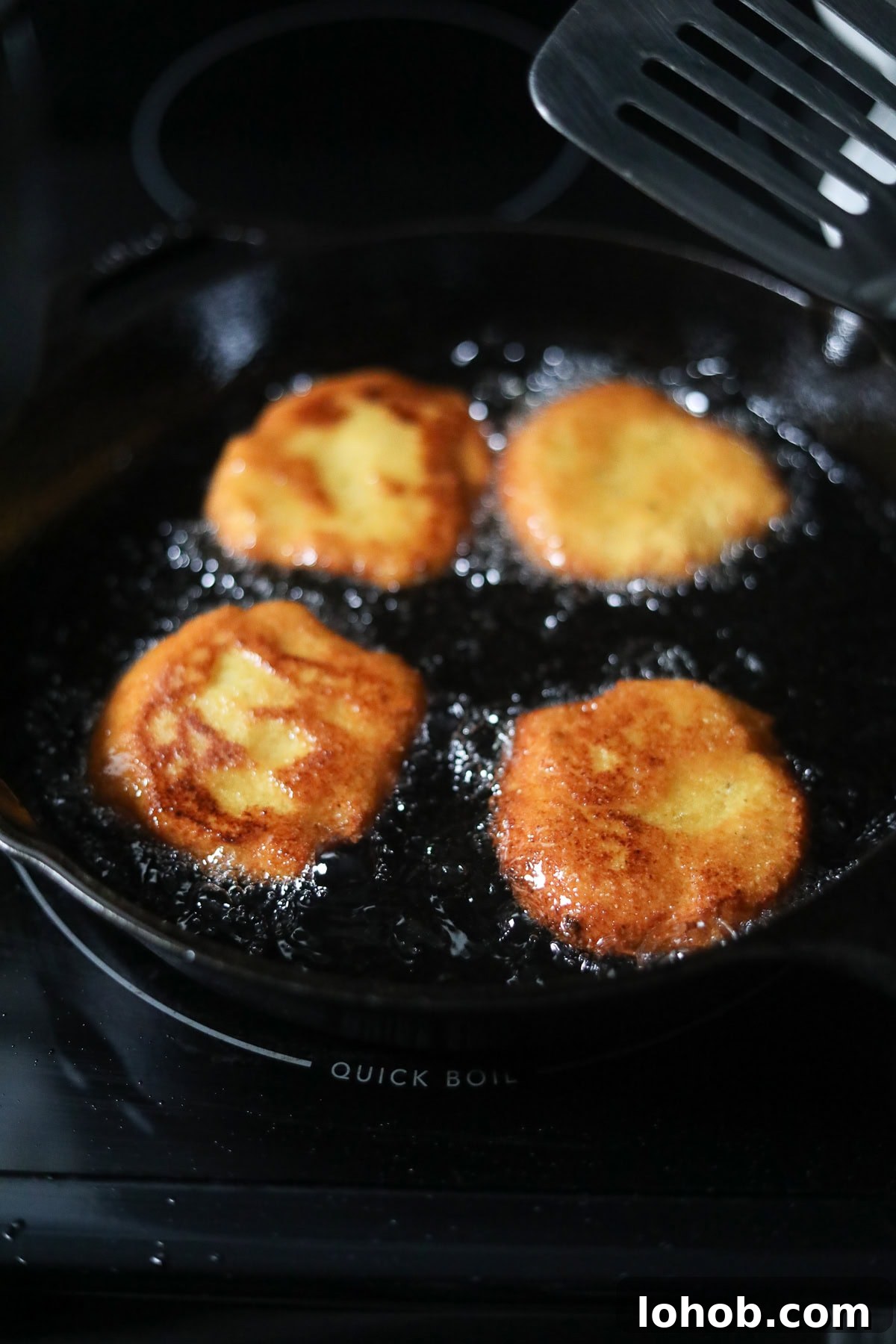 Southern Hot Water Cornbread Recipe — Crispy Skillet Cornbread 7 Hot water cornbread patties frying in hot oil.