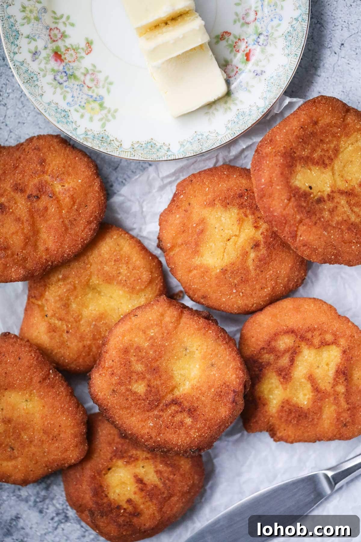 Southern Hot Water Cornbread Recipe — Crispy Skillet Cornbread 8 Hot water cornbread spread out on a gray surface.