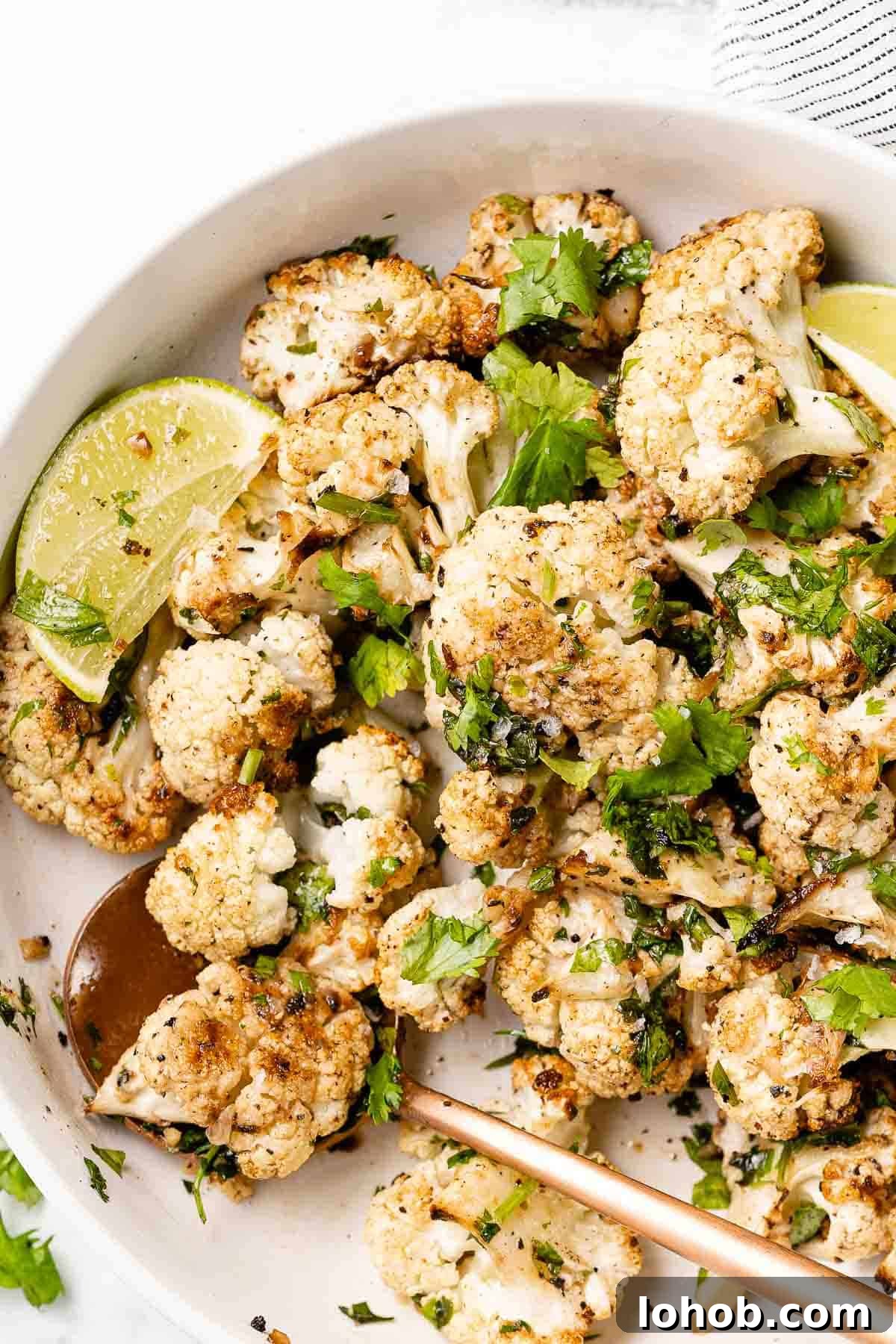 cilantro lime roasted cauliflower in white bowl with spoon
