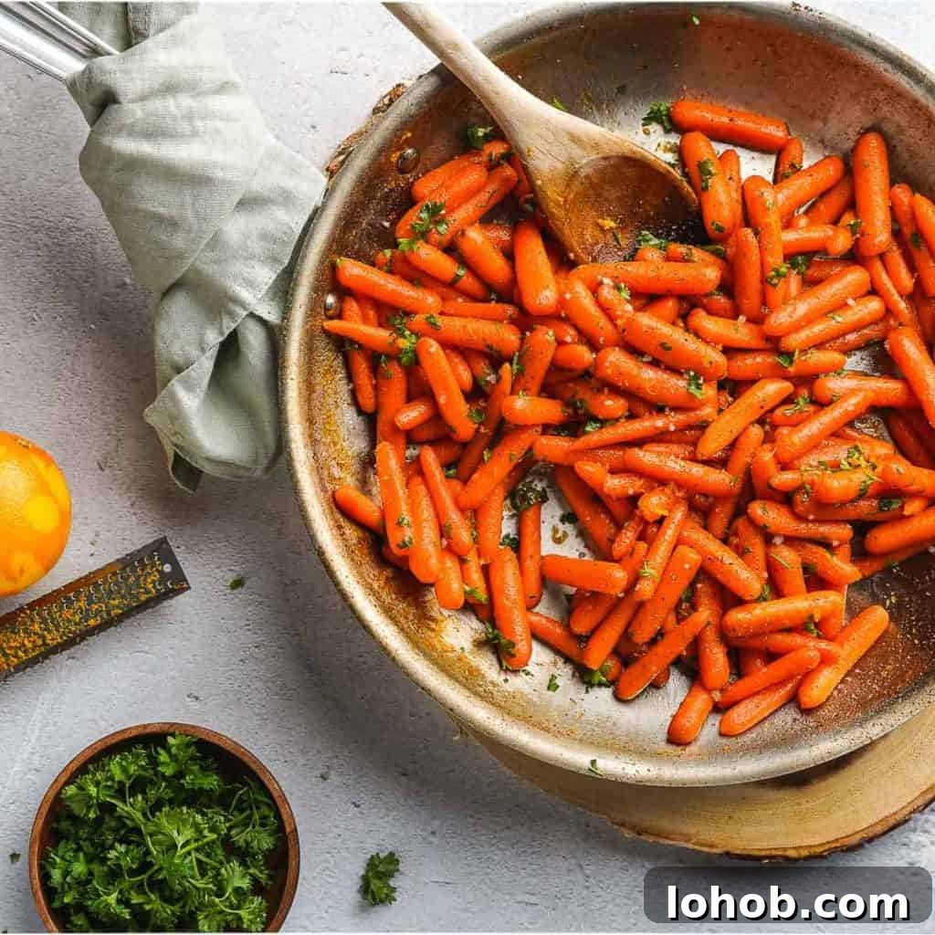 Easy Honey Orange Glazed Carrots in pan with garnishes on the side