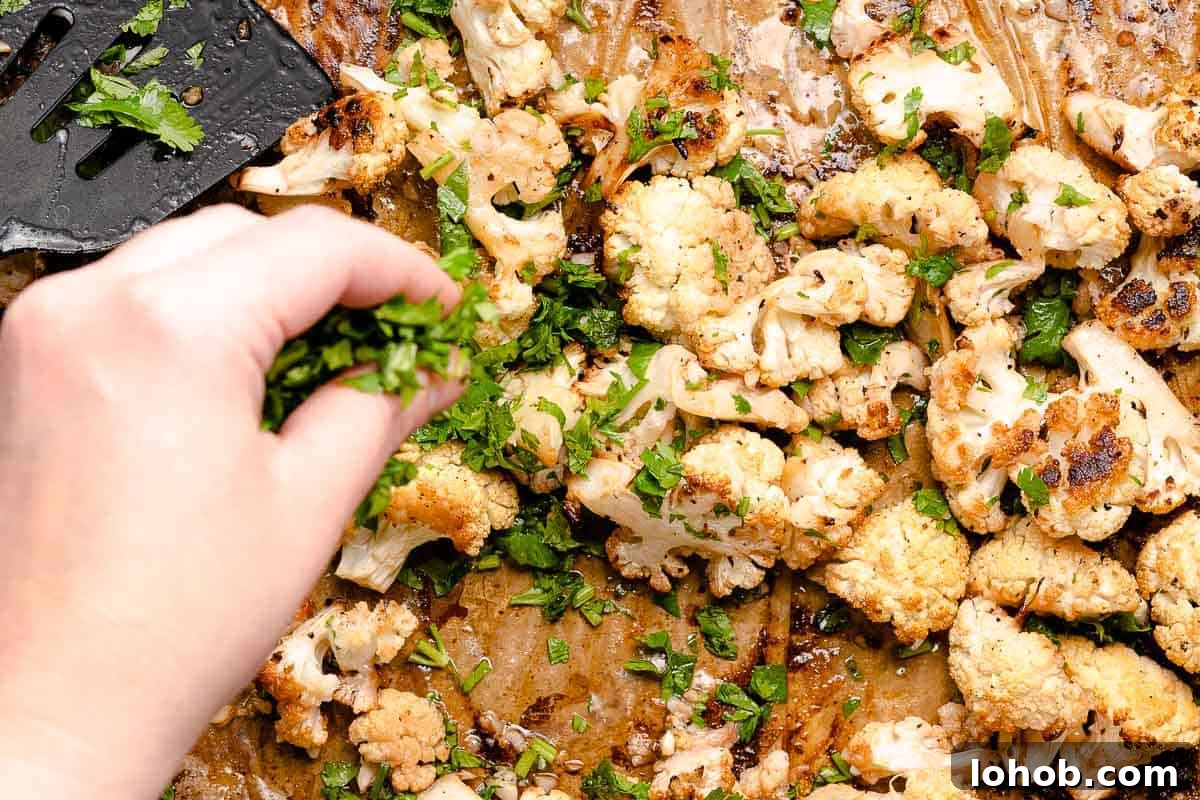 hand sprinkling chopped cilantro over roasted cauliflower