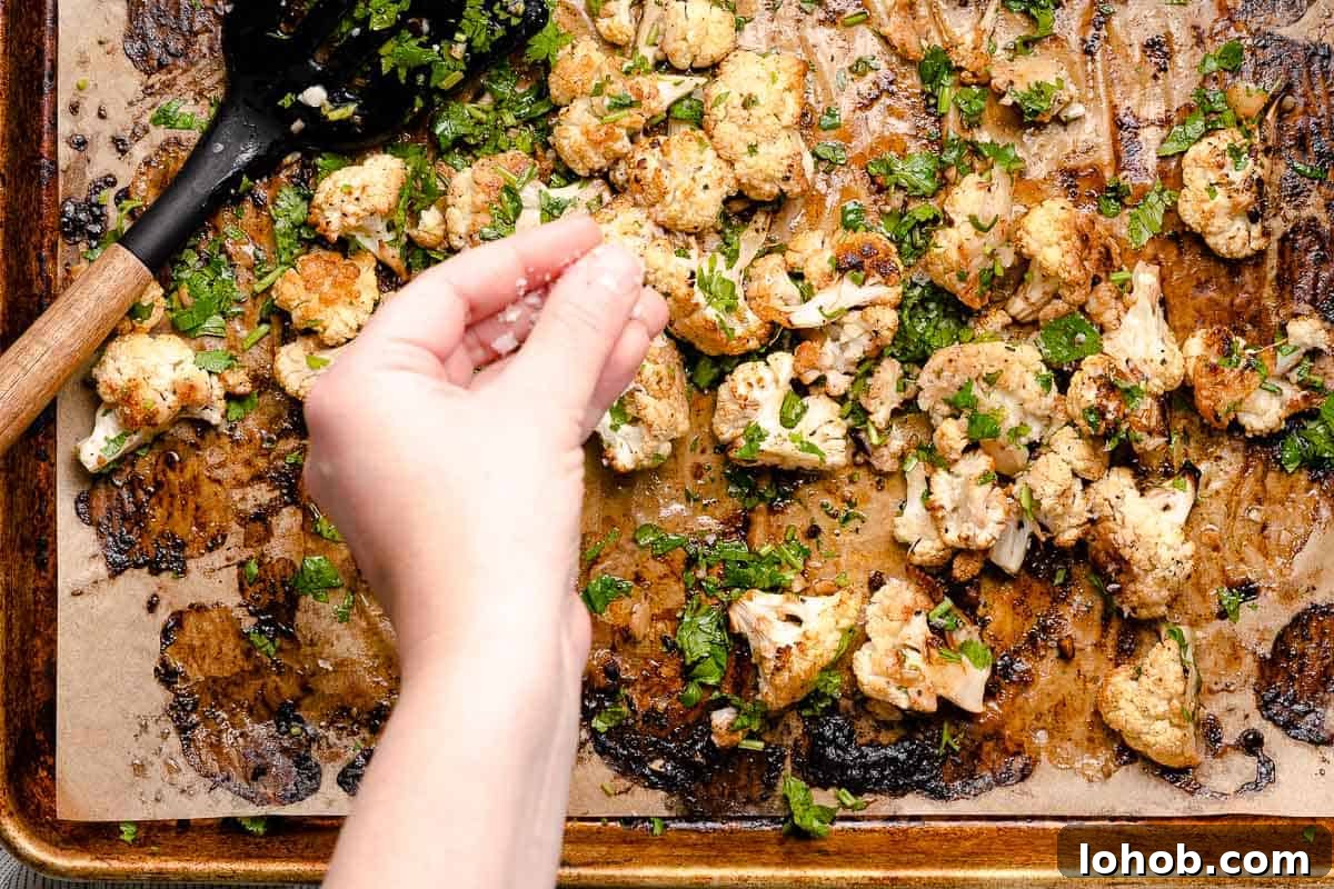 hand sprinkling flaky sea salt overtop roasted cauliflower