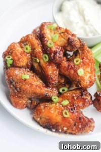 stacked honey garlic chicken wings cooked to perfection, golden brown and garnished with slivers of green onions