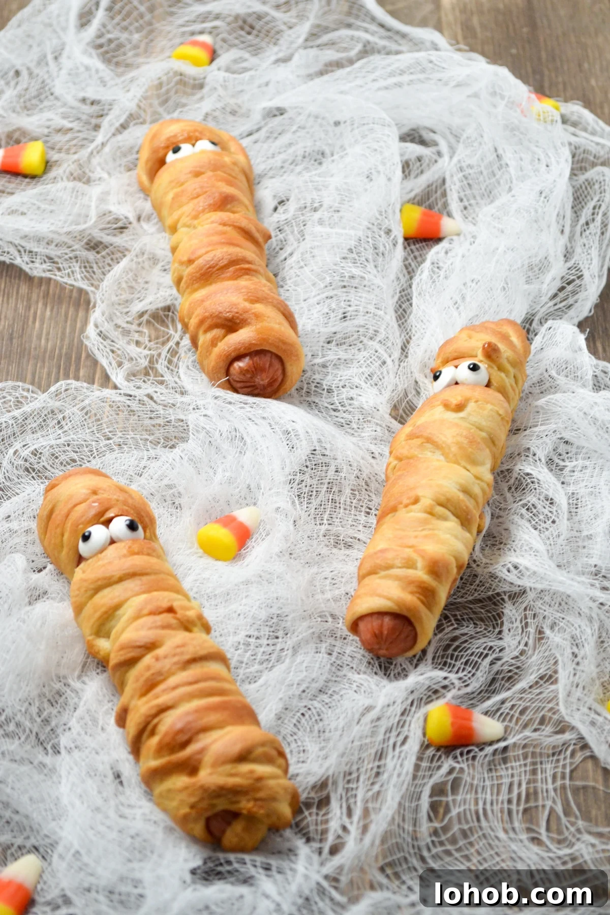Crispy Mummy Hot Dogs for Halloween – Air Fryer & Oven Guide 8 3 mummy hot dogs, laying on cheesecloth.