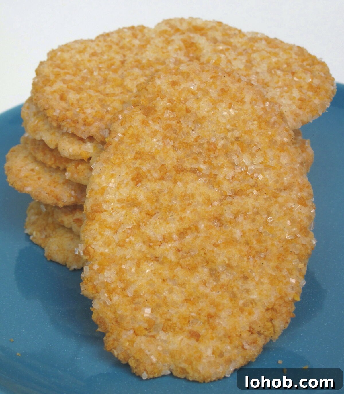 Crispy Frosted Flakes Sugar Cookies in a stack on a blue plate with one cookie in front showing sugar and cereal topping.