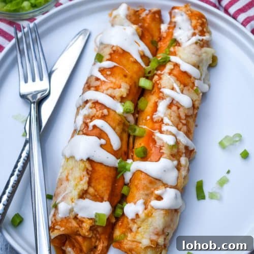 Buffalo Chicken Enchiladas with Creamy Ranch Sauce 8 two buffalo chicken enchiladas topped with a drizzle of ranch dressing and sliced green onions on a white plate