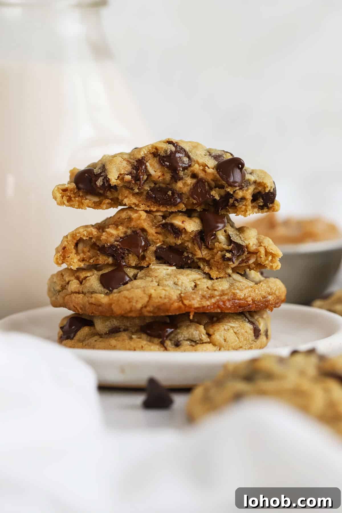 gluten-free peanut butter oatmeal cookies stacked on a white dessert plate next to a bottle of milk
