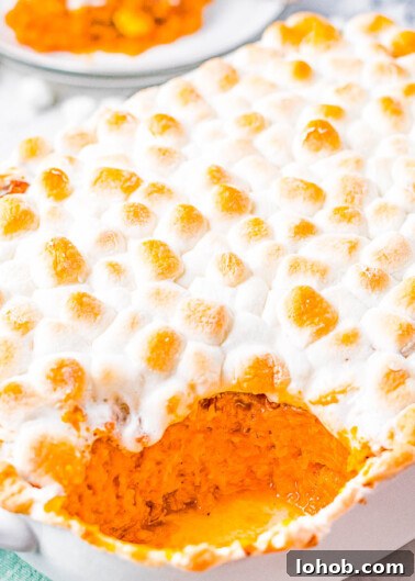 Classic Marshmallow Sweet Potato Casserole in a baking dish with a scoop missing.