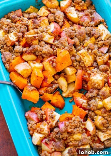 A spoon stuck into a baking dish with sweet potatoes and apple casserole.