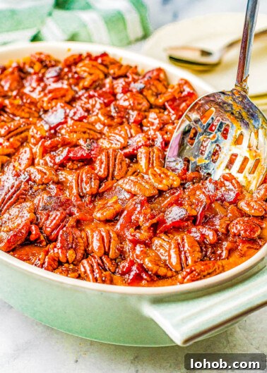 Savory Sweet Potato Casserole with Candied Bacon in a casserole dish with a slotted spoon sticking out.