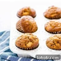 Gluten Free Apple Muffins in a white muffin pan on a blue and white striped kitchen towel.