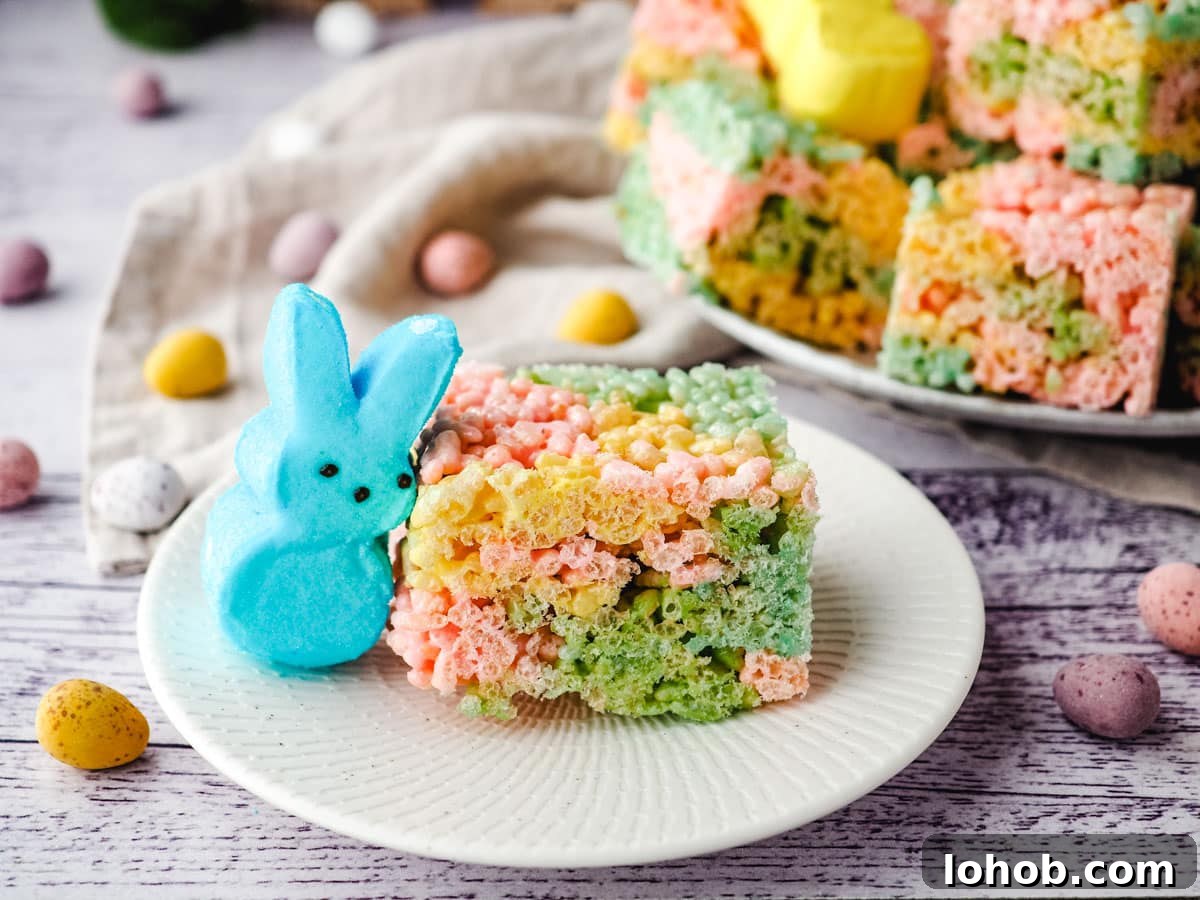 Peeps rice krispie treat on a plate with a Peep on the side and plate with rest of treats in the background.