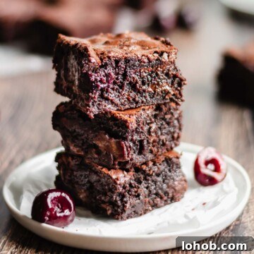 Stack of three cut brownies to expose the cherries inside.