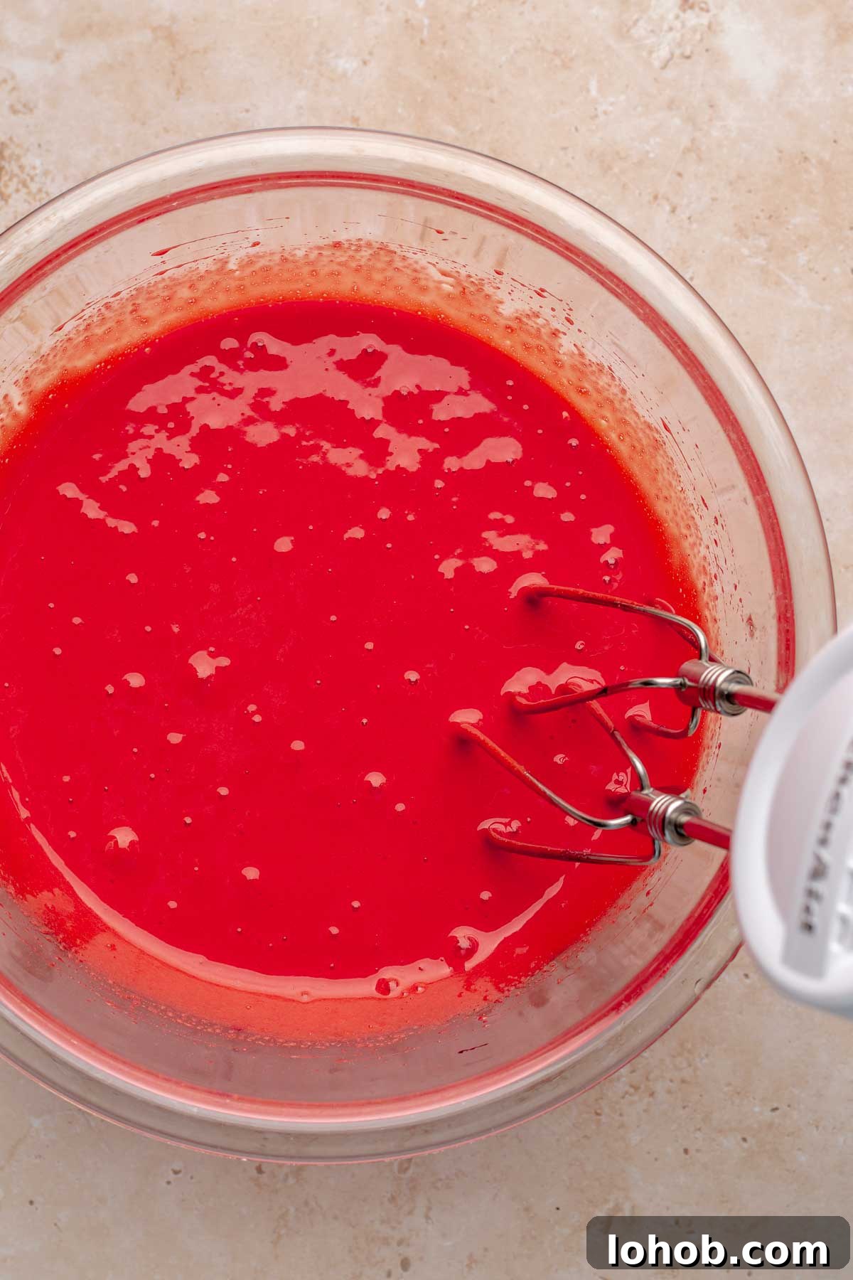 Fudgy Red Velvet Brownies with Cream Cheese Swirl 5 A hand mixer mixes red batter in a bowl.