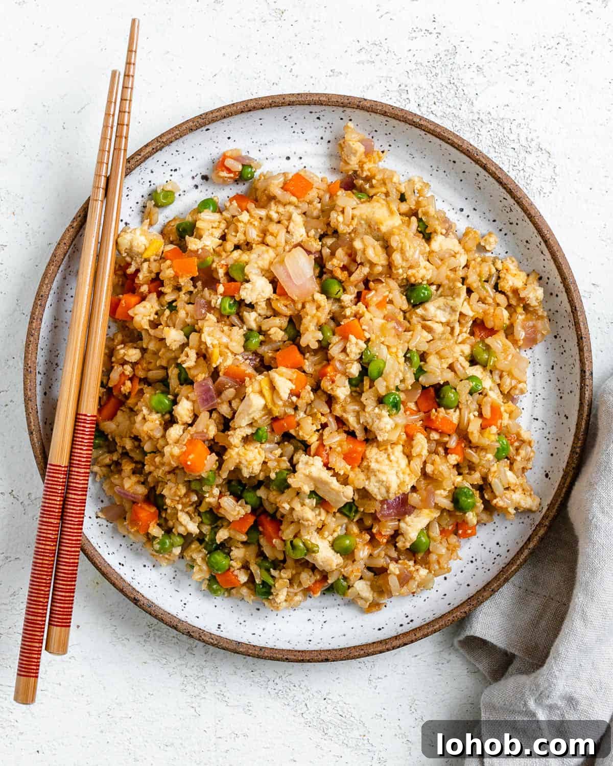 completed Easy Vegetable Brown Fried Rice plated on a white plate against a light background alongside chopsticks