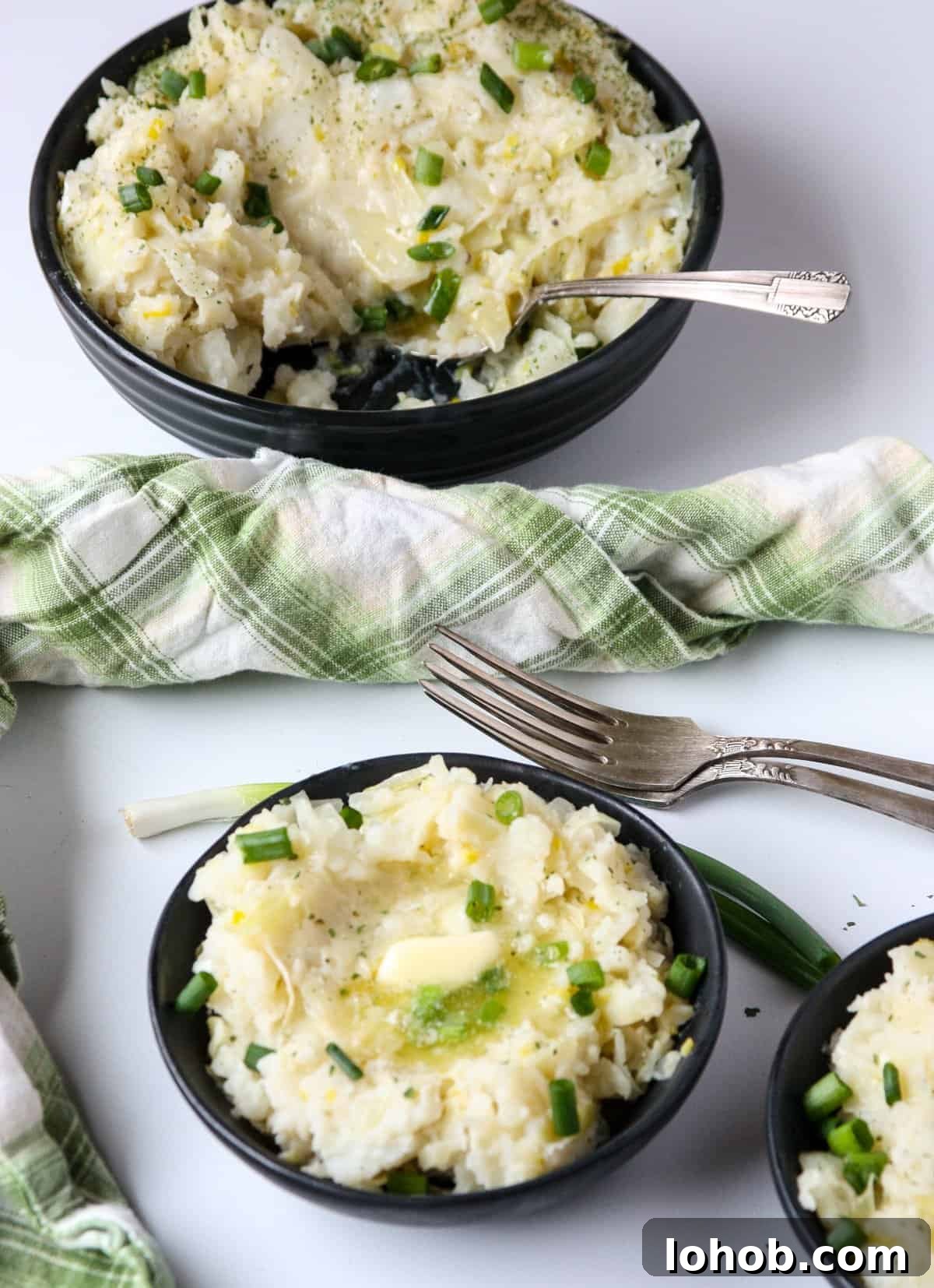 Colcannon: Traditional Irish Mashed Potatoes with Cabbage 7 Mashed Potatoes in three black bowls on a white table.
