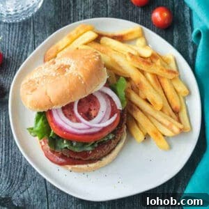 Savory Chickpea Veggie Burger Recipe for Juicy Plant-Based Patties 12 Chickpea veggie burger topped with tomoato and red onion next french fries.
