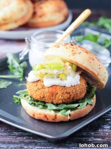 Autumn Vegan Burger with arugula, mayo, and caramelized leeks on an onion roll. The top half of the roll rests to the side of the burger.