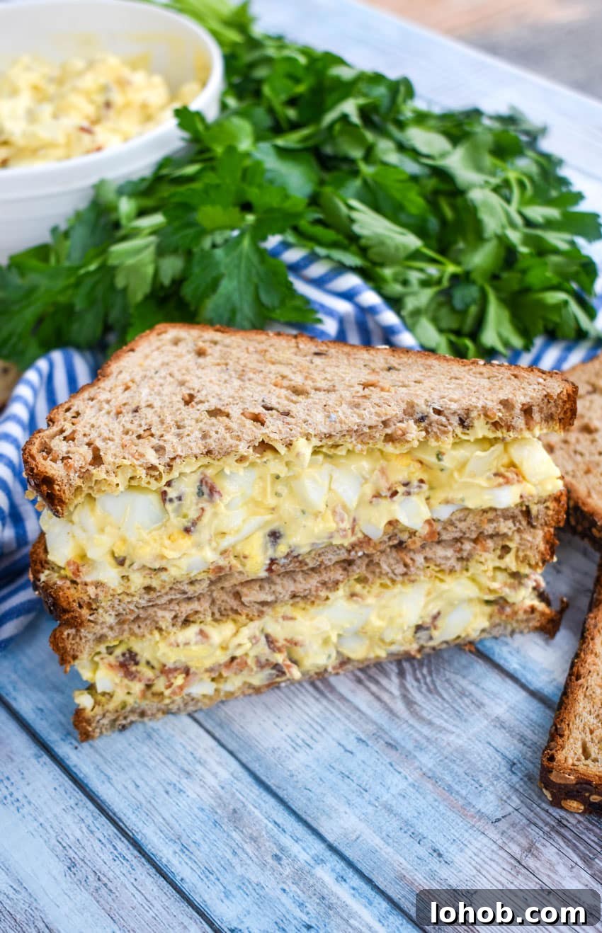 Creamy Bacon Ranch Egg Salad Recipe for Sandwiches & Bowls 6 two halves of bacon ranch egg salad sandwiches stacked together on a wooden table