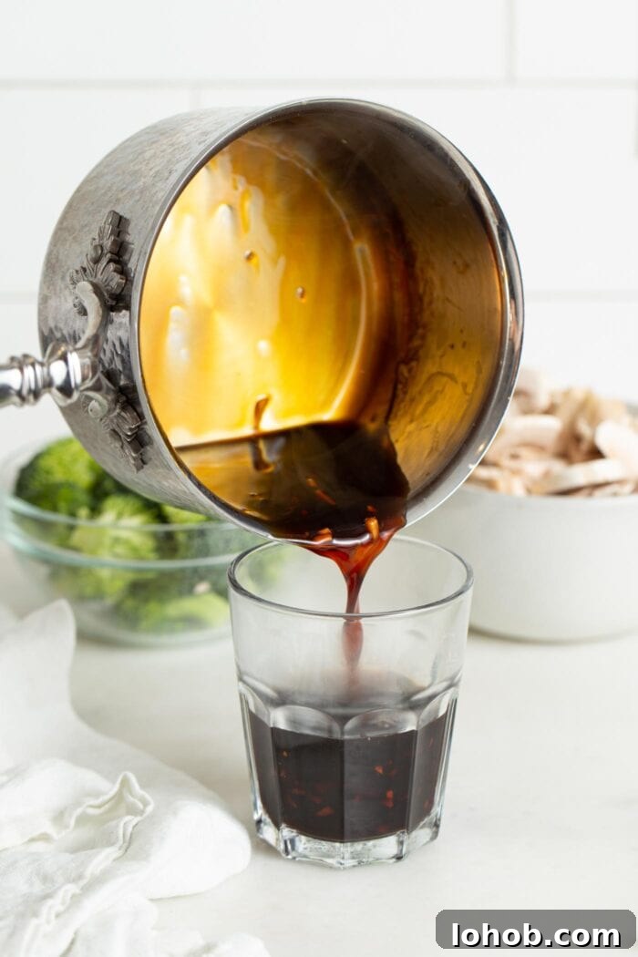 Pouring a saucepan of teriyaki sauce into a glass cup.
