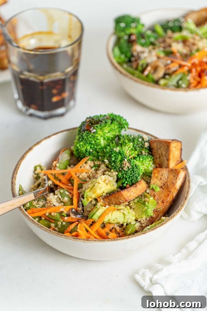 Quinoa, carrot, broccoli and tofu mixed up in a bowl with a fork.
