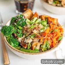 A colorful teriyaki quinoa and tofu bowl with carrot, broccoli and avocado.