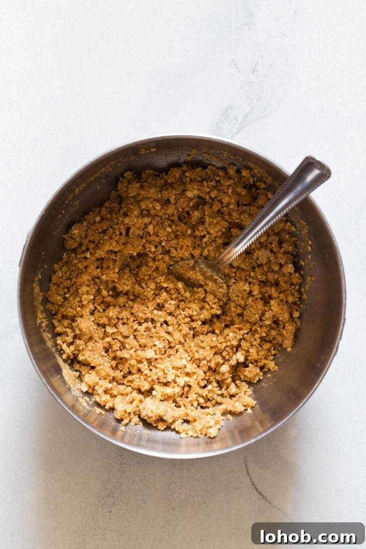 Mixing graham cracker crumbs with butter in a bowl